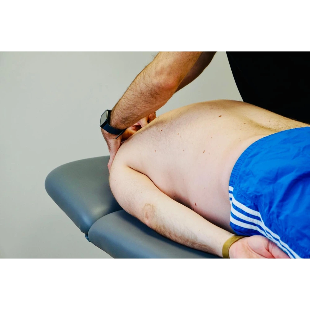 Pacjent leżący na stole i ręce fizjoterapeuty